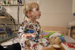 gutt som sitter på en sykehusseng