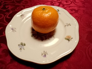 En mandarin på en tallerken. En mandarin gir meg minner fra barndommens magiske jul. 